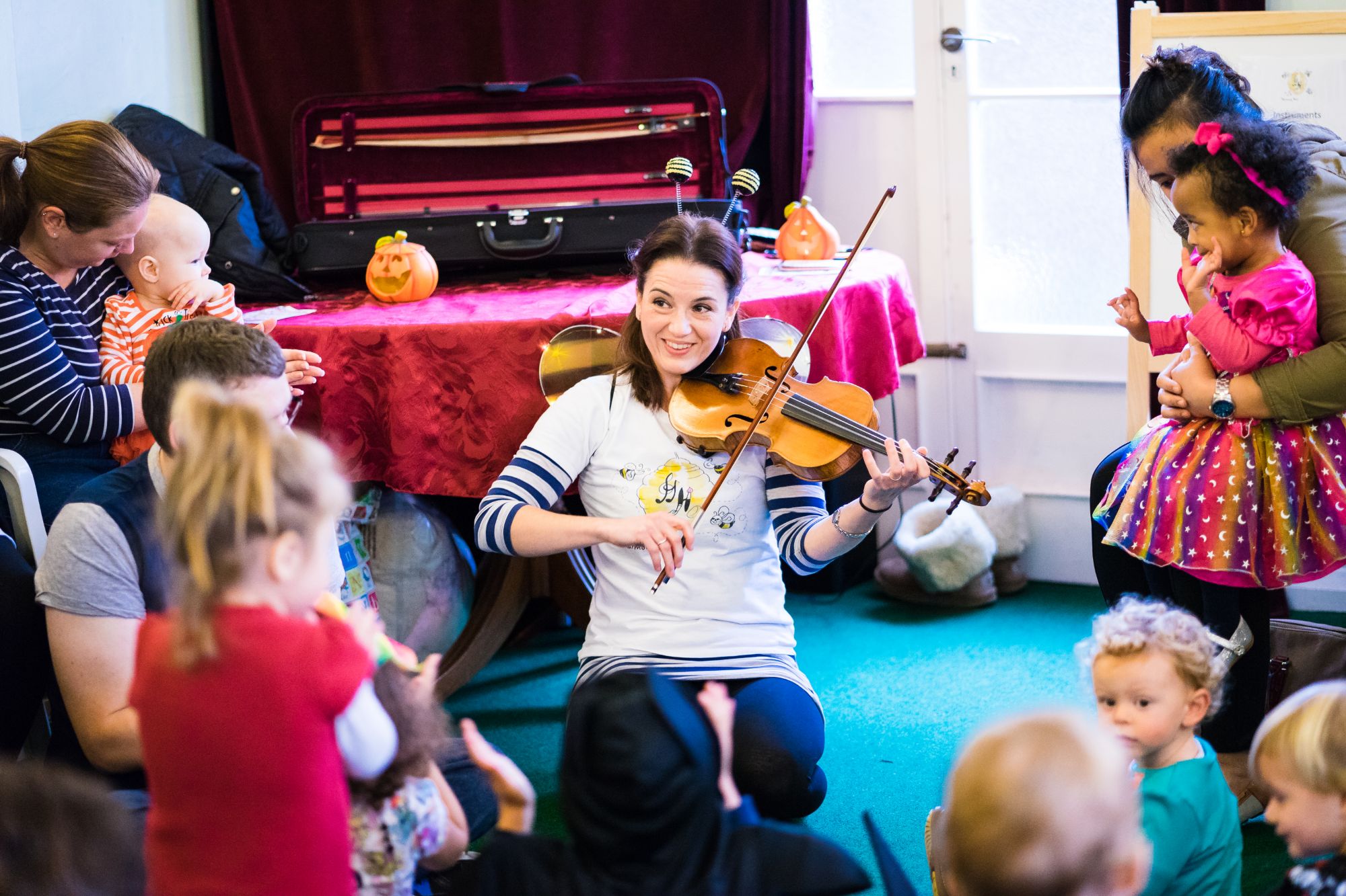 A violinist playing for babies, toddlers and their parents at a music class